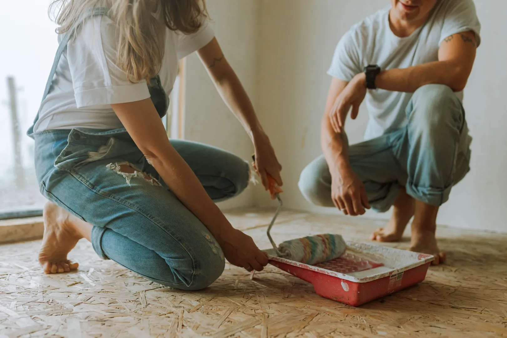 two people with paint on floor, installing flooring